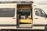 This RV rental shows an open camper van, revealing a cozy interior with a bed, laptop, and small counter. Perfect for travel.