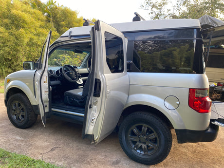 Silver Honda Element pop-top camper with open doors, an ideal RV rental for your next outdoor adventure.