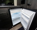 Open mini-fridge in an RV rental, built into dark wood cabinetry. Interior shelves are empty, ready for your trip's food.