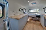 Spacious rv rental interior featuring a cozy bed, ample wood countertops, and practical storage solutions.