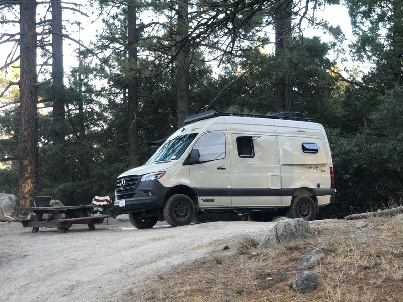  a rustic wooden building with trees under a clear blue sky.|This Mercedes-Benz Sprinter rv rental camper van — photo 13