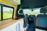 RV rental van's interior: kitchenette, front seats, and scenic outdoor view through windows.