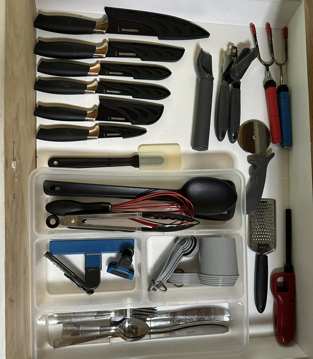 Efficient RV rental kitchen drawer: Organized knives, cooking tools like spatulas & whisks, silverware, and grater. — photo 12