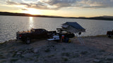 Sunset at a lake campsite. Truck with an overlanding trailer & rooftop tent offers an amazing outdoor RV rental experience.