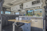 Spacious RV rental interior featuring a kitchenette, dining area, and scenic views, ideal for van life adventures.