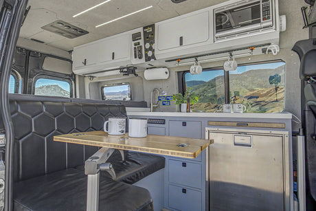Spacious RV rental interior featuring a kitchenette, dining area, and scenic views, ideal for van life adventures.