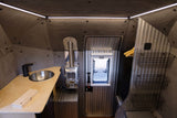 Compact rv rental interior featuring a modern kitchen sink, Dickinson stove, window, and smart storage for your adventure.