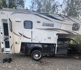 This white Lance truck camper, a type of RV rental, is ready for adventure. Open door & outdoor step visible.