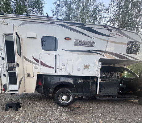 This white Lance truck camper, a type of RV rental, is ready for adventure. Open door & outdoor step visible.