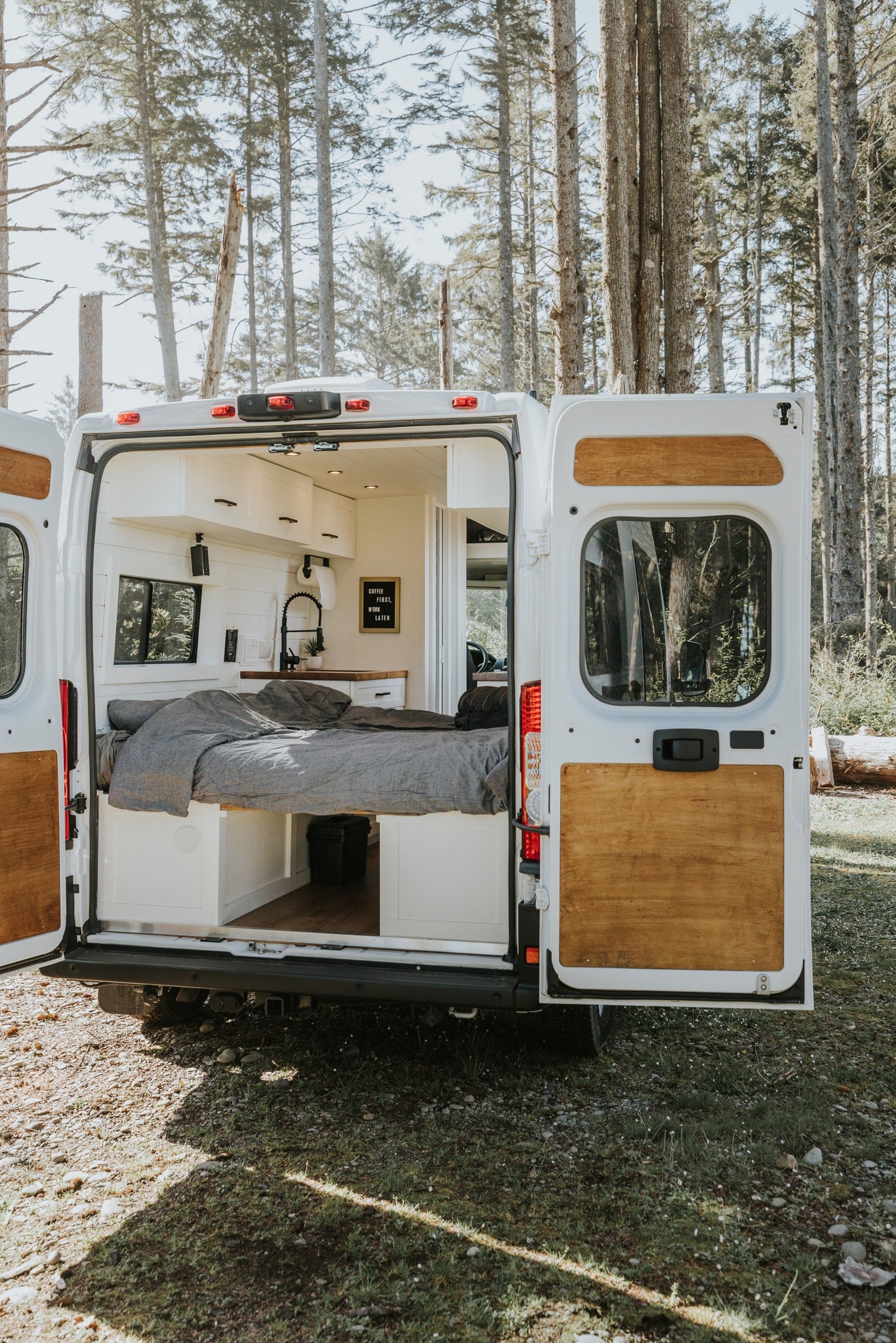 Explore the comfortable interior of this camper van, perfect for an rv rental adventure amidst nature. Rear doors open. — photo 6