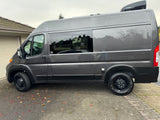 Sleek gray camper van, ideal for RV rental. Side view with windows, roof AC unit, and external electrical connection.