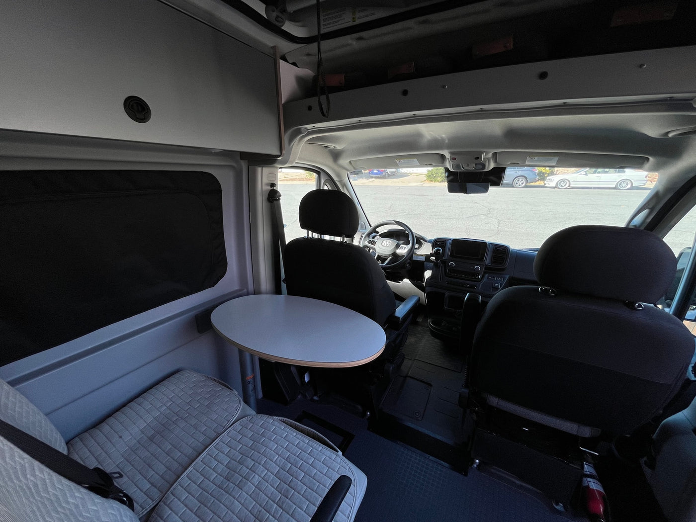 Spacious RV rental interior featuring front cabin, passenger table, and quilted bench seating for comfortable travel. — photo 11
