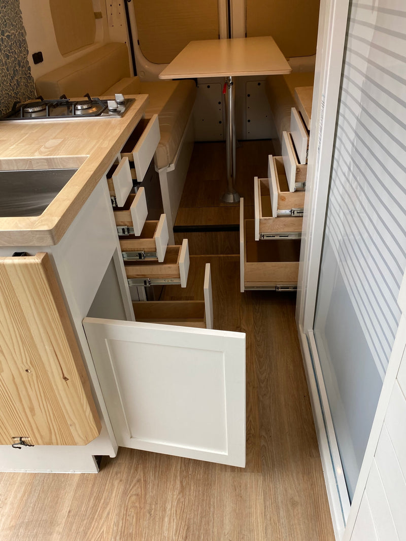Clean RV rental interior: integrated kitchen with stove, dining table, and abundant pull-out storage drawers designed for efficiency. — photo 8