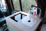 Compact RV rental kitchen featuring a modern induction cooktop, sink, and faucet, perfect for on-the-go cooking.