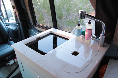 Compact RV rental kitchen featuring a modern induction cooktop, sink, and faucet, perfect for on-the-go cooking.