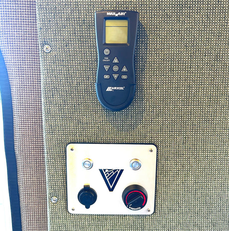 RV rental interior view: MAX X AIR fan remote and Webasto heater controls mounted on a woven fabric wall.