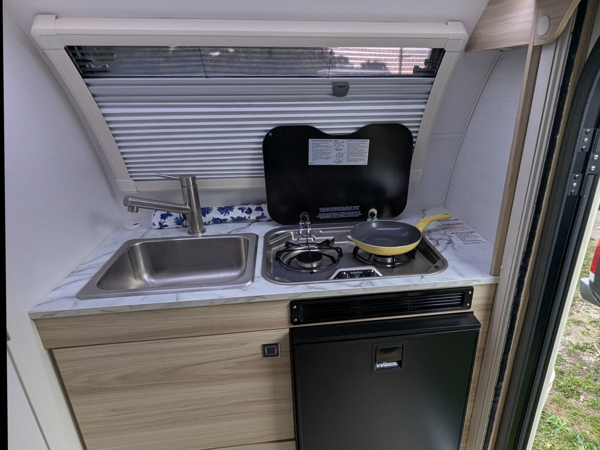  gas off). A green power light glows.|Inside a cozy rv rental: a grey sofa — photo 7