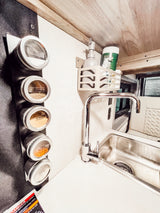 Compact RV rental kitchen featuring magnetic spice jars (salt, pepper), a modern sink, and mounted soap dispenser.