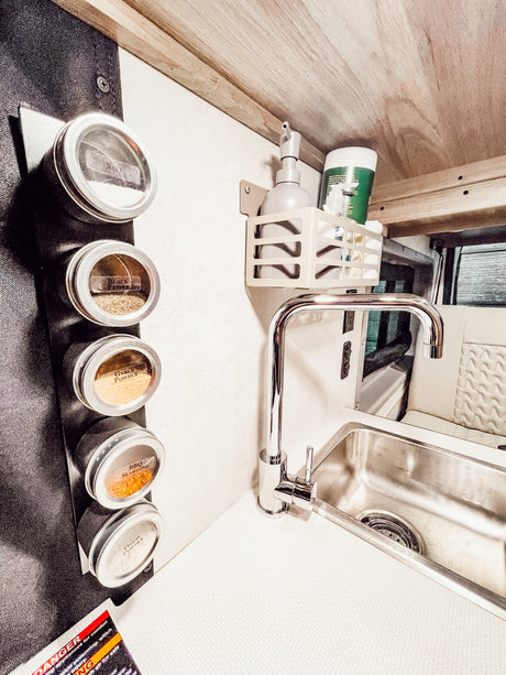 Compact RV rental kitchen featuring magnetic spice jars (salt, pepper), a modern sink, and mounted soap dispenser.
