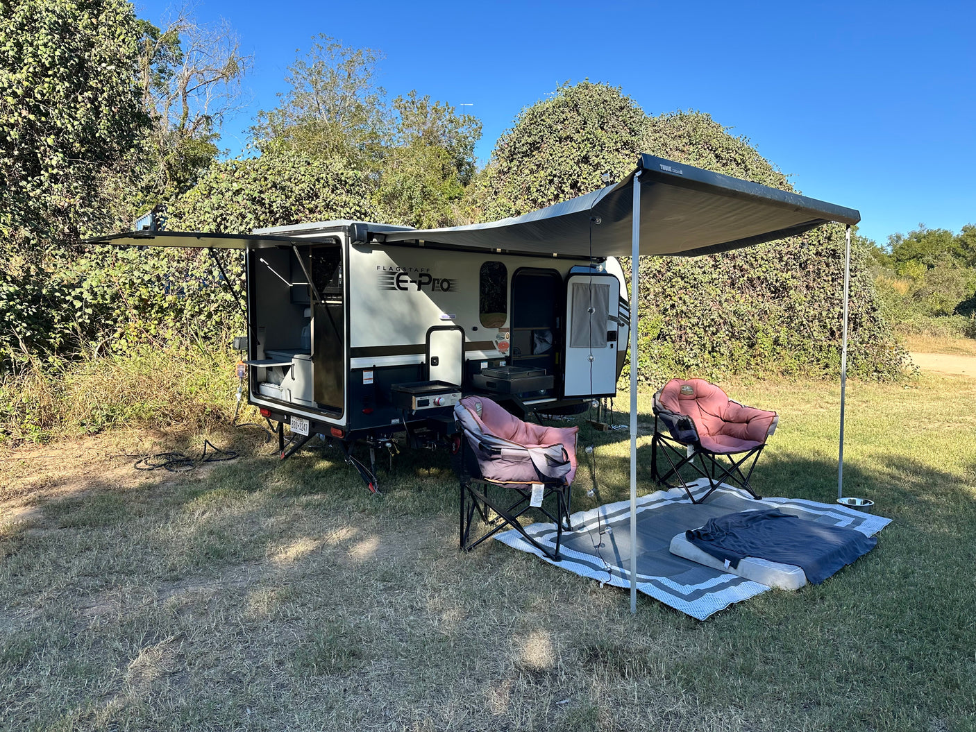 This Flagstaff E-Pro RV rental is perfectly set up for camping, featuring an extended awning, chairs, and outdoor kitchen.