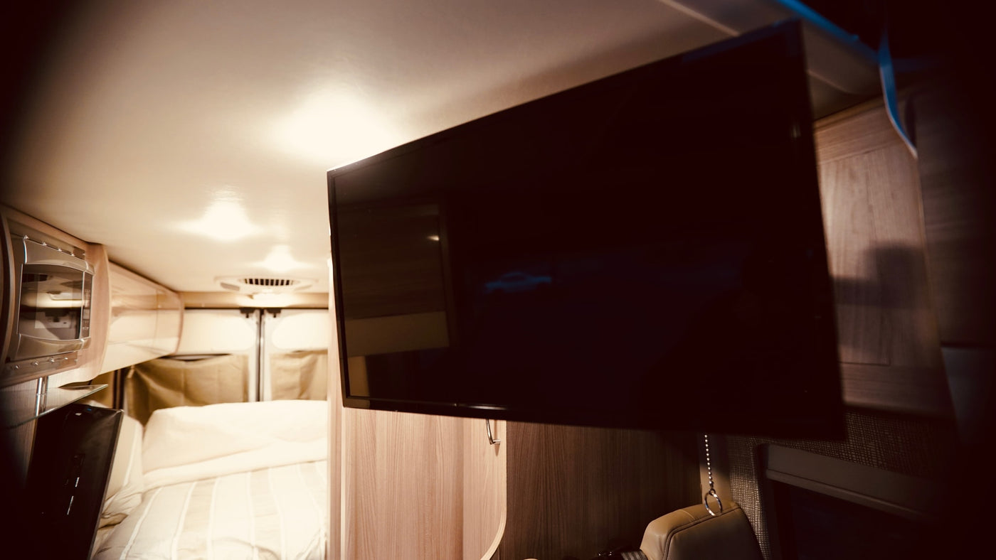 Inside a comfortable RV rental, featuring a mounted TV, microwave, and cozy bed. Ideal for travel adventures. — photo 8