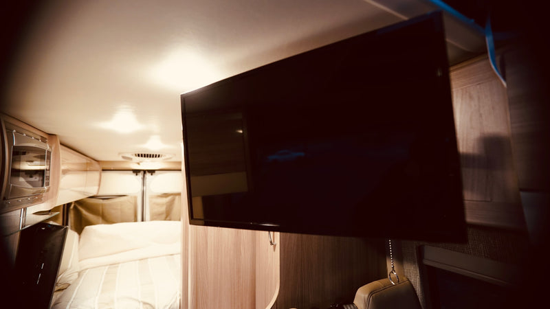 Inside a comfortable RV rental, featuring a mounted TV, microwave, and cozy bed. Ideal for travel adventures. — photo 8