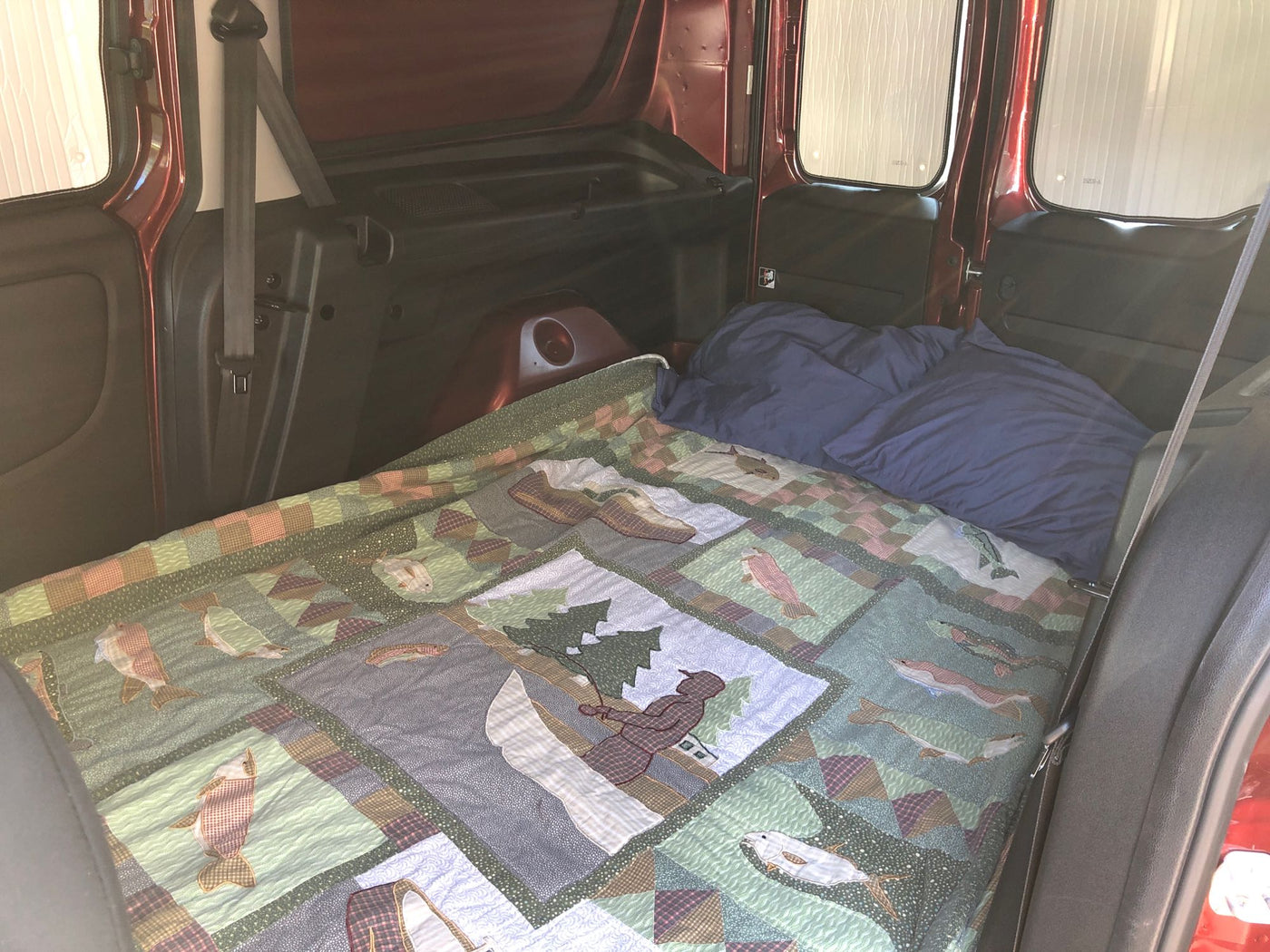 Cozy bed setup in an RV rental, featuring a beautiful nature-themed quilt for comfortable van camping. — photo 8