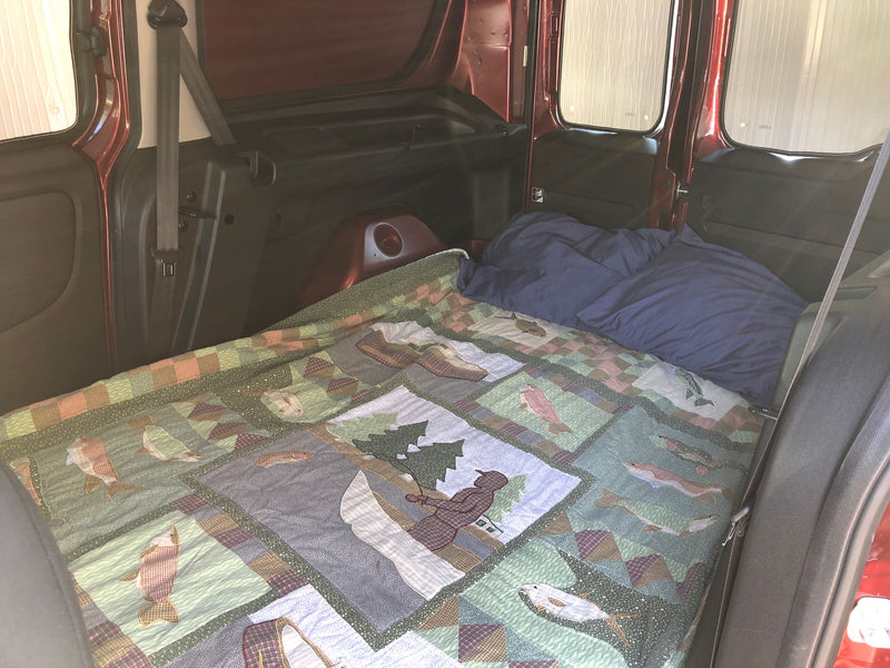 Cozy bed setup in an RV rental, featuring a beautiful nature-themed quilt for comfortable van camping. — photo 8