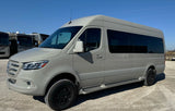 Light grey Mercedes Sprinter camper van, equipped for adventure, parked in an RV rental lot under blue skies.
