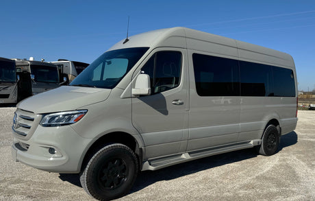Light grey Mercedes Sprinter camper van, equipped for adventure, parked in an RV rental lot under blue skies.