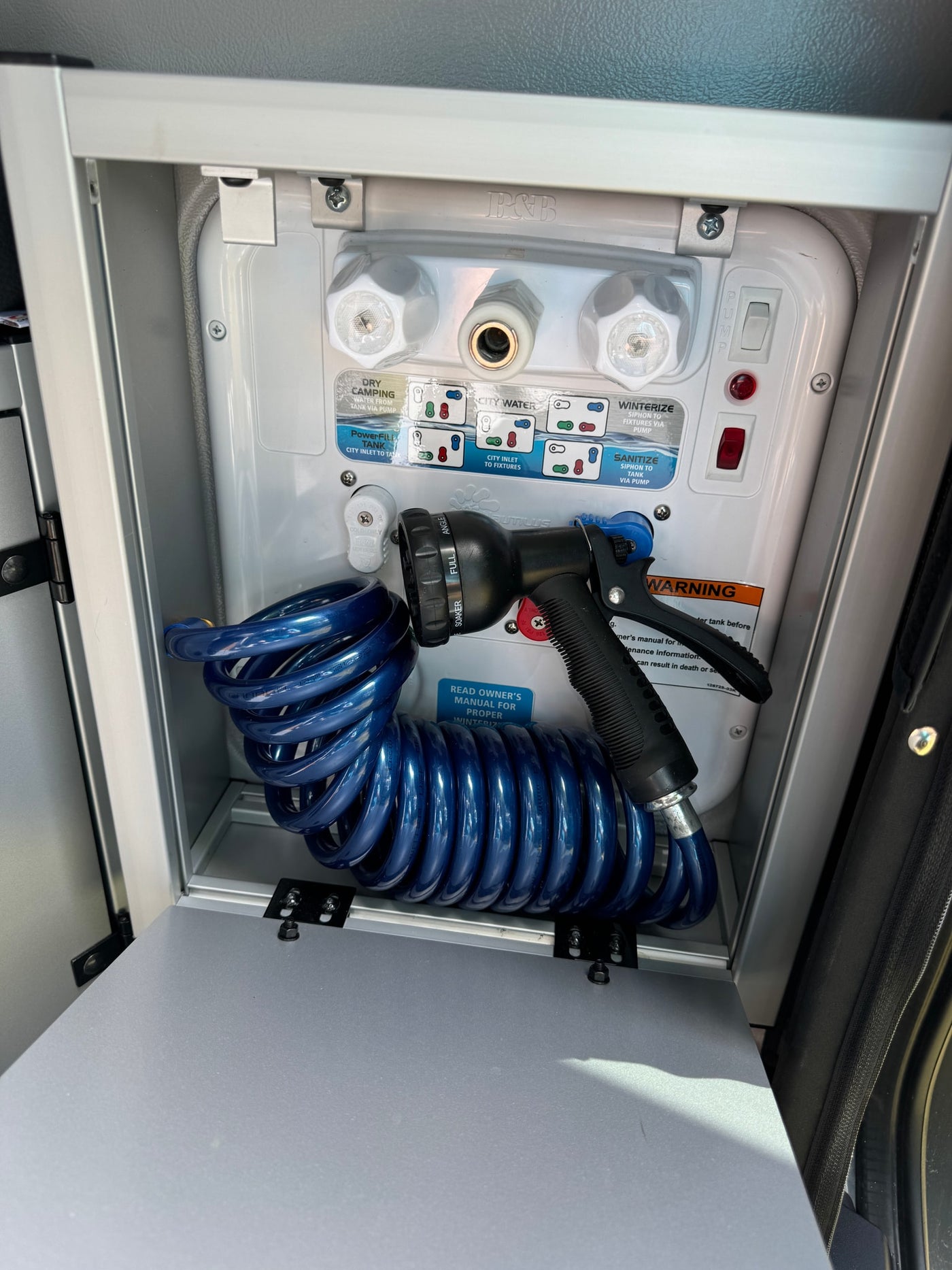 RV rental water utility hub: Nautilus panel, coiled hose, and nozzle for fresh water, city hookup, and winterizing. — photo 9
