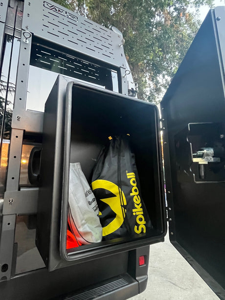 RV rental storage box open on the rear of a van, holding a Spikeball game. Perfect for outdoor fun and adventure gear.