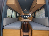 Cozy RV rental interior: spacious camper van with bamboo woodwork, comfy benches, and a central table, perfect for mobile living.