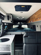 This **RV rental** shows a compact, modern interior with a comfy bed, mini-kitchen, and plush seating, ideal for adventure.