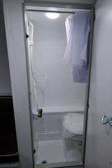 This compact wet bath inside an RV rental features a shower, toilet, and curtain, offering essential facilities for travelers.