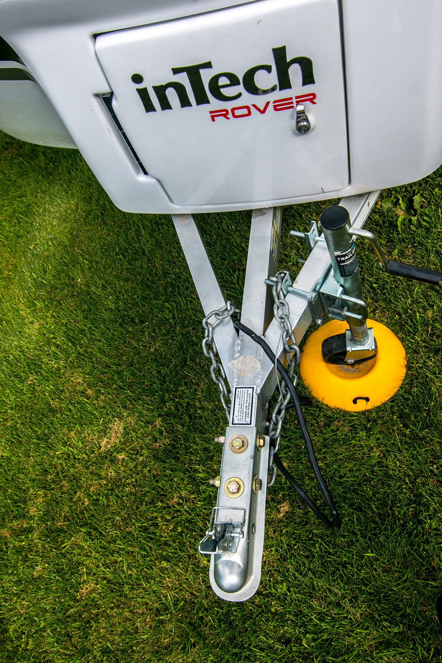 Close-up of an inTech ROVER travel trailer's hitch and jack, set on grass, perfect for RV rental camping.