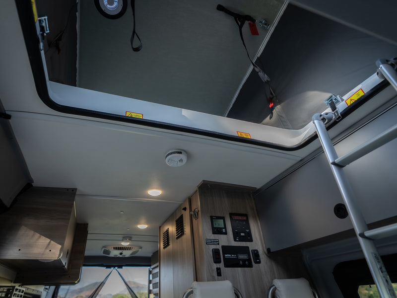 RV rental interior: Overhead bunk with ladder access, digital control panel, and a smoke detector for safety. — photo 17