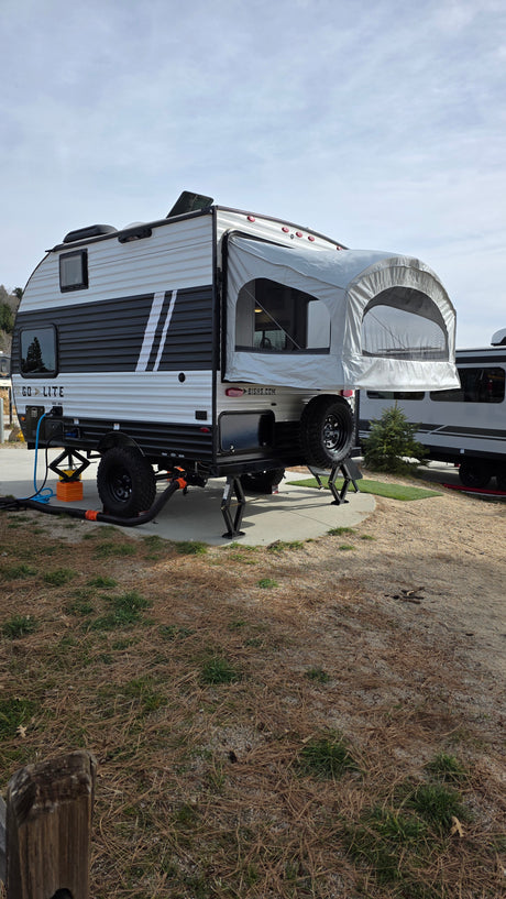 This black & white Go Lite hybrid travel trailer rv rental is set up at a campsite with hookups, ready for adventures.