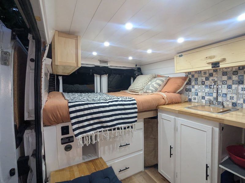  surrounded by a pine forest with mountains in the background.|Two people share a cheerful meal inside a cozy rv rental camper van — photo 17