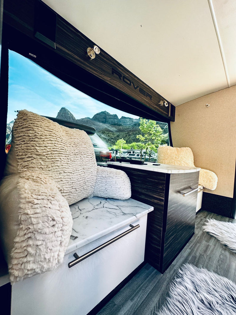  and an open archway revealing the campsite.|Enjoying the outdoors with an RV rental! A teardrop trailer with an open kitchen and awning is set up at a scenic campsite.|Inside a comfy rv rental — photo 14