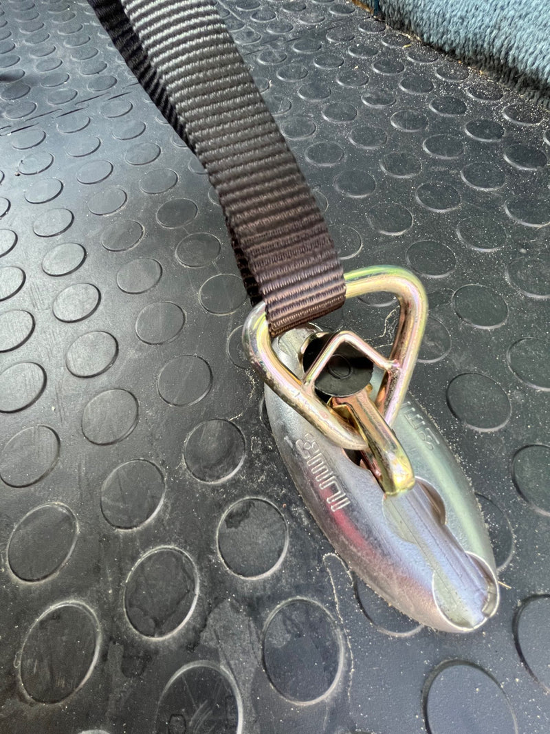 Secure your gear in your rv rental! This shows a tie-down strap and buckle on a rubber mat inside an RV. — photo 10