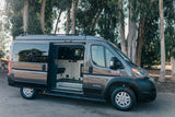 Gray Ram ProMaster camper van for rv rental, parked outdoors with its side door open, showing a custom interior.