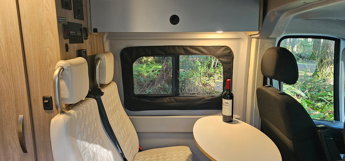 Relaxing rv rental space: comfortable seating, a table with wine, and a serene forest view through the window.