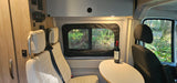 Relaxing rv rental space: comfortable seating, a table with wine, and a serene forest view through the window.