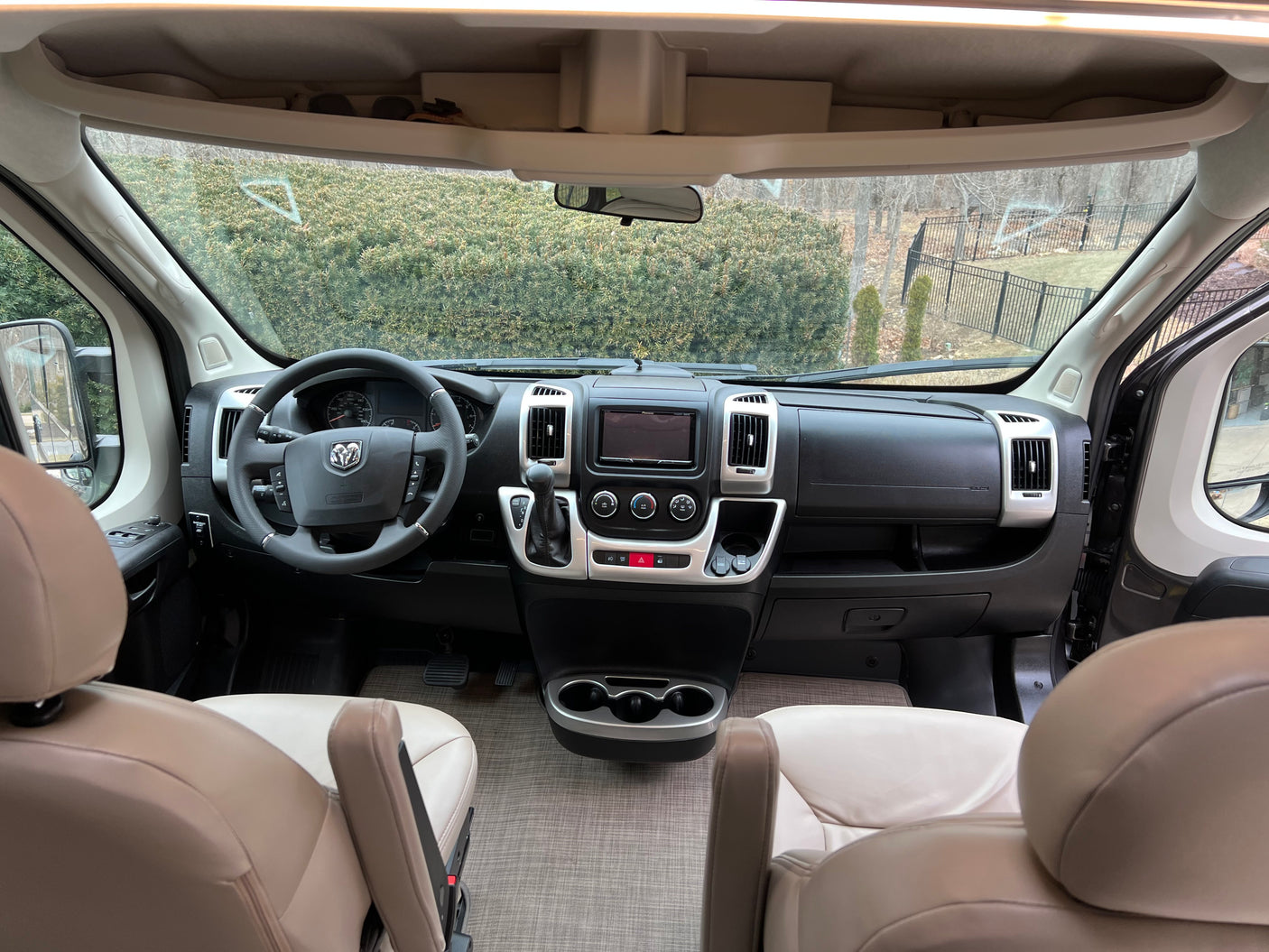Interior of a modern RV rental, featuring the driver's cockpit with steering wheel, dashboard, and light-colored seats.