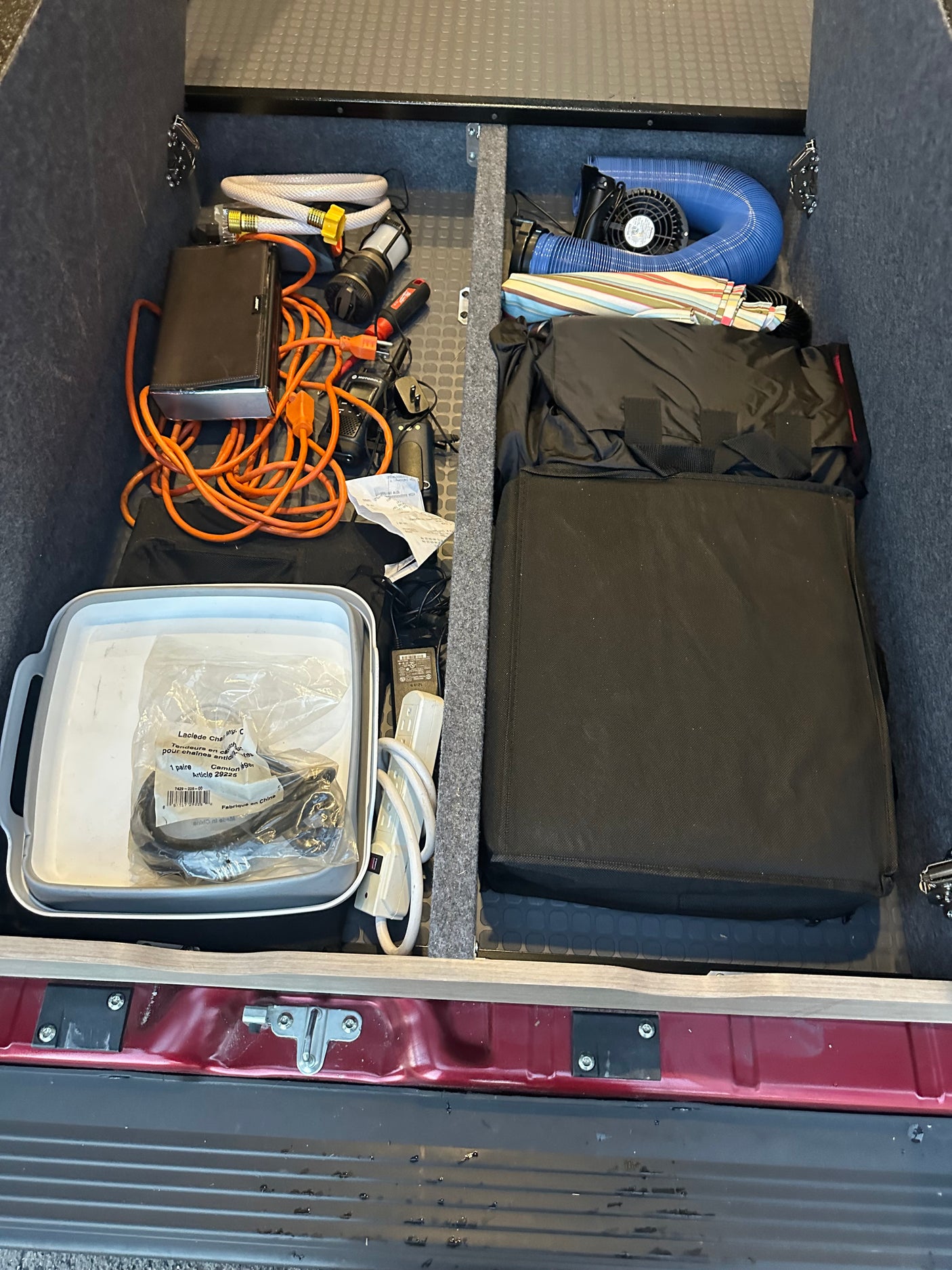 RV rental's rear storage, meticulously organized with hoses, power cords, fan, and essential camping gear.