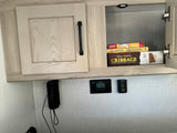 Open RV rental cabinet with games & books above a solar controller (97) and thermostat (90), showing interior storage & controls.