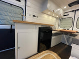 Bright, modern RV rental interior: a compact kitchen with a sink & fridge, and a cozy dinette space.