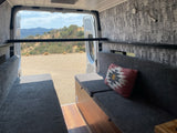 RV rental with comfy grey benches, owl wallpaper, and a metal bar. Enjoy mountain views from this camper van interior.