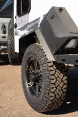 Close-up of a rugged TigerMoth off-road RV rental, showing its knobby Goodyear Wrangler tire and durable body. Perfect for adventure!
